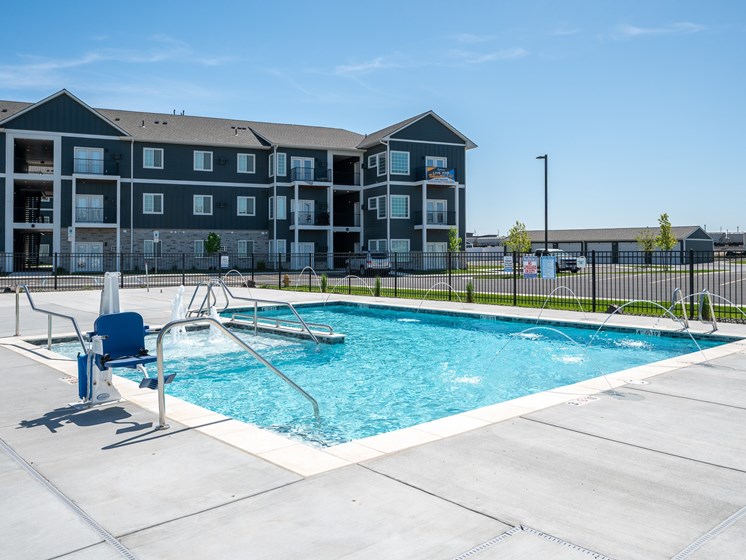 A swimming pool in front of a multi-story apartment building.